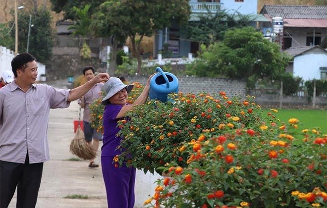 Người dân cahwm sóc các lu hoa ngũ sắc trồng dọc ven những con đường bê tông ở Nghĩa Phúc.